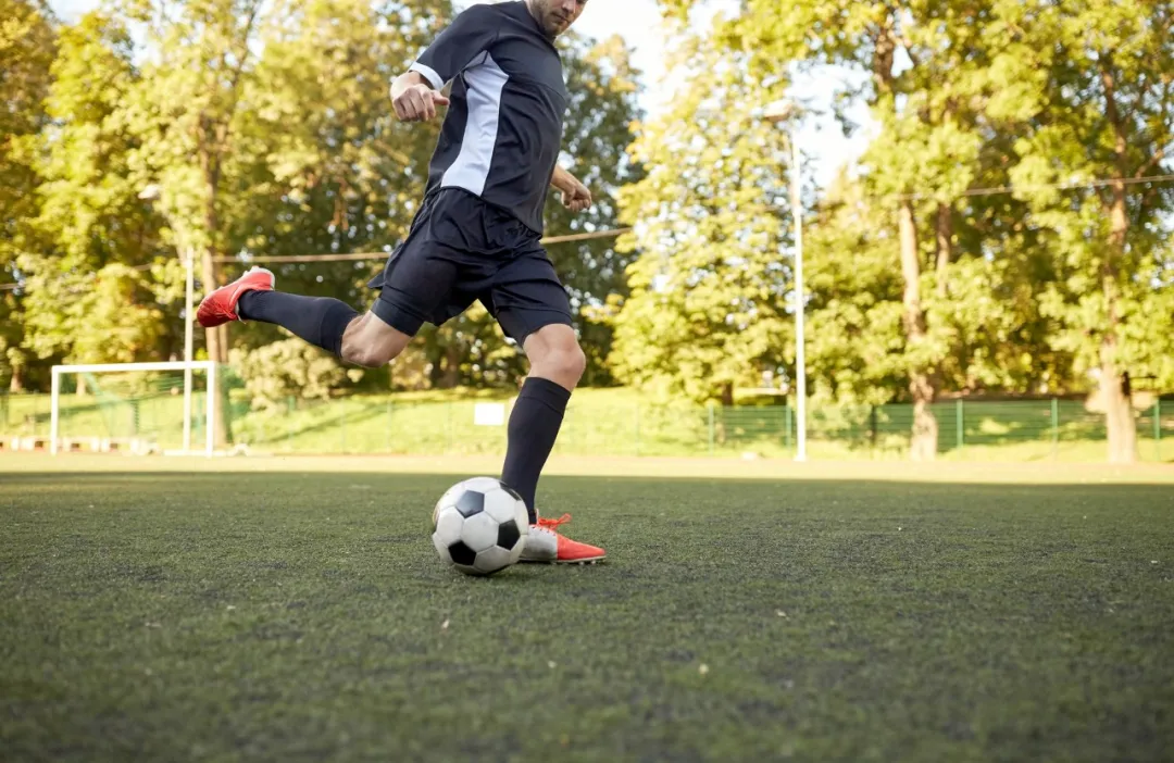 Soccer player on field mid-kick — ankle sprains are common in pivoting sports like football