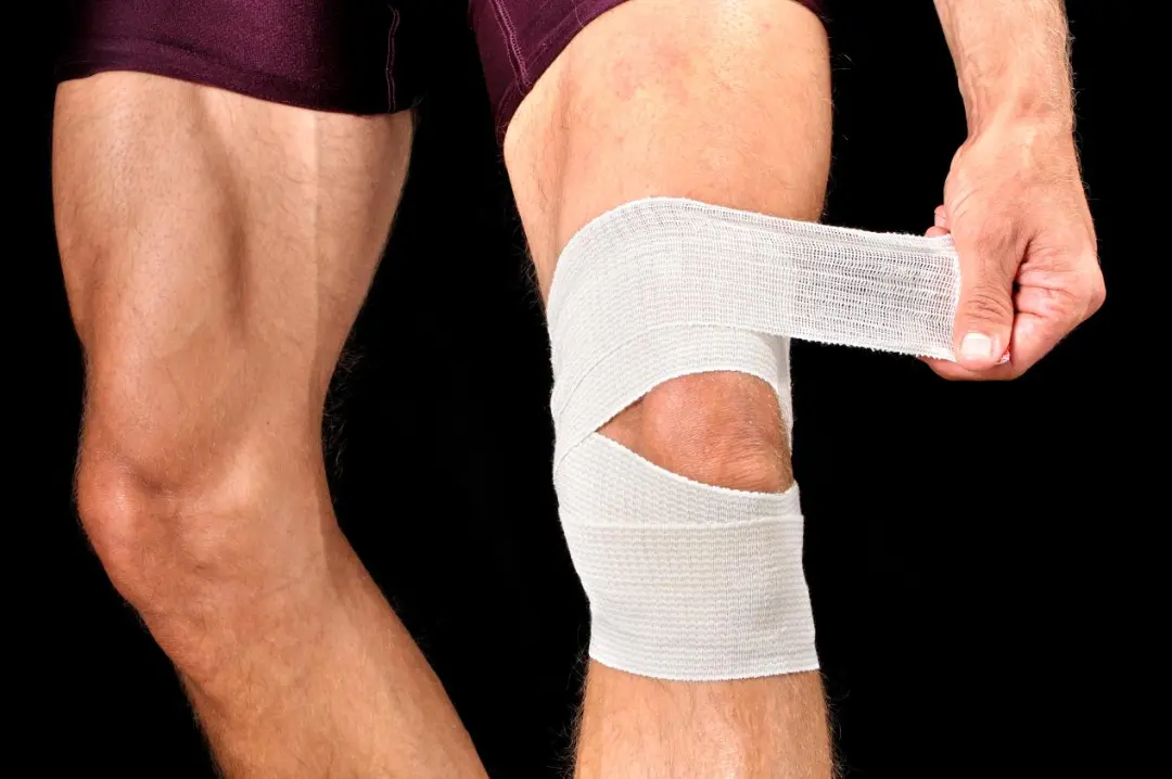 Person wrapping a bandage around the knee after activity-related discomfort