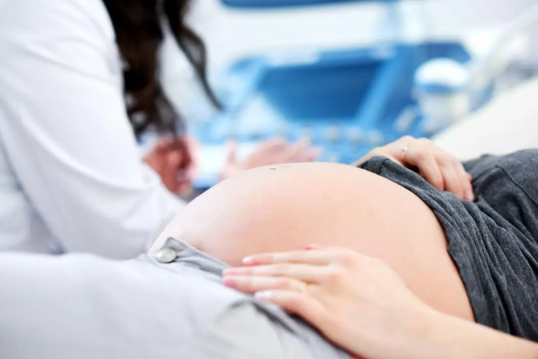 An expectant mother gently holding her pregnant belly