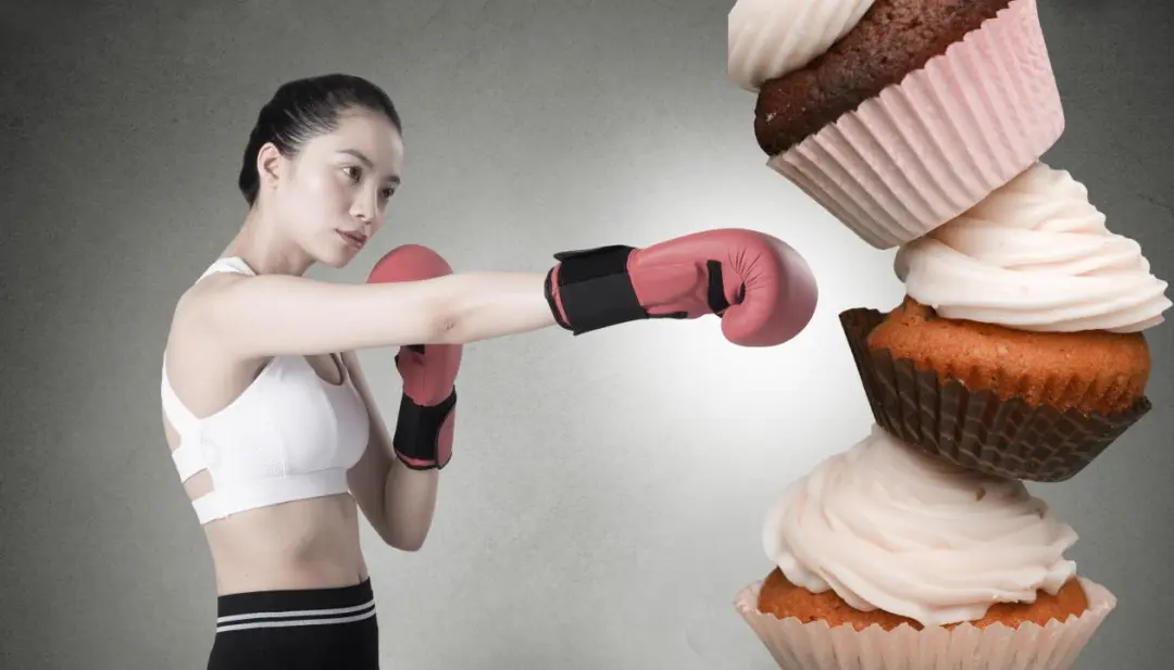 Woman in boxing gloves punching away cupcakes - symbolizing the fight against weight regain